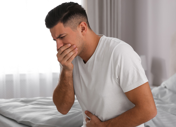 man suffering from nausea on bed at home. food poisoning